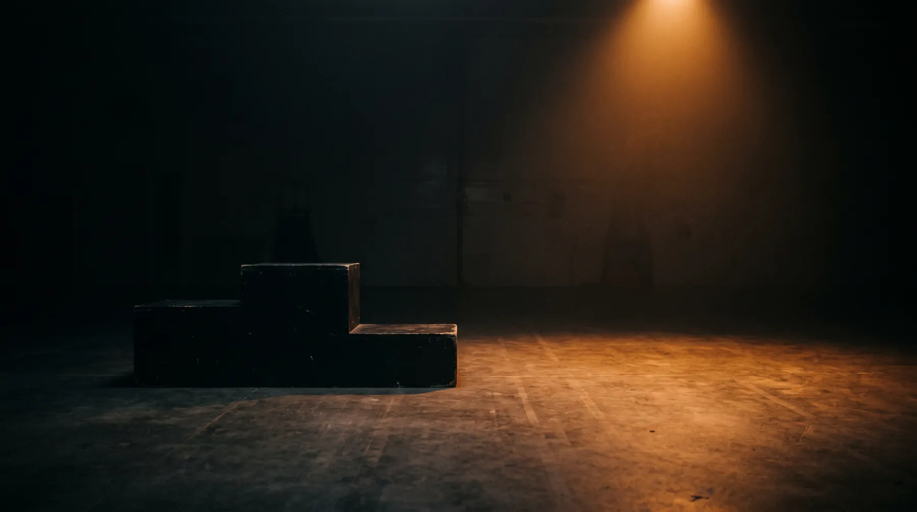 An empty podium in the dark, with a single warm light on the floor beside it